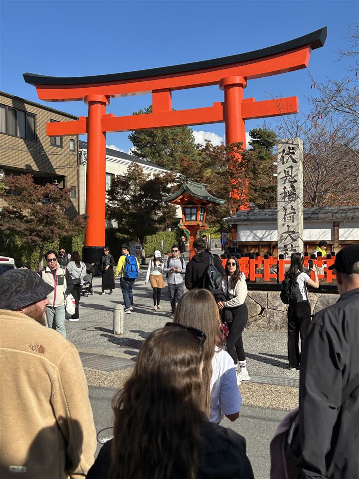The large vermilion torii gate at the entrance to Fushimi Inari Taisha, with crowds